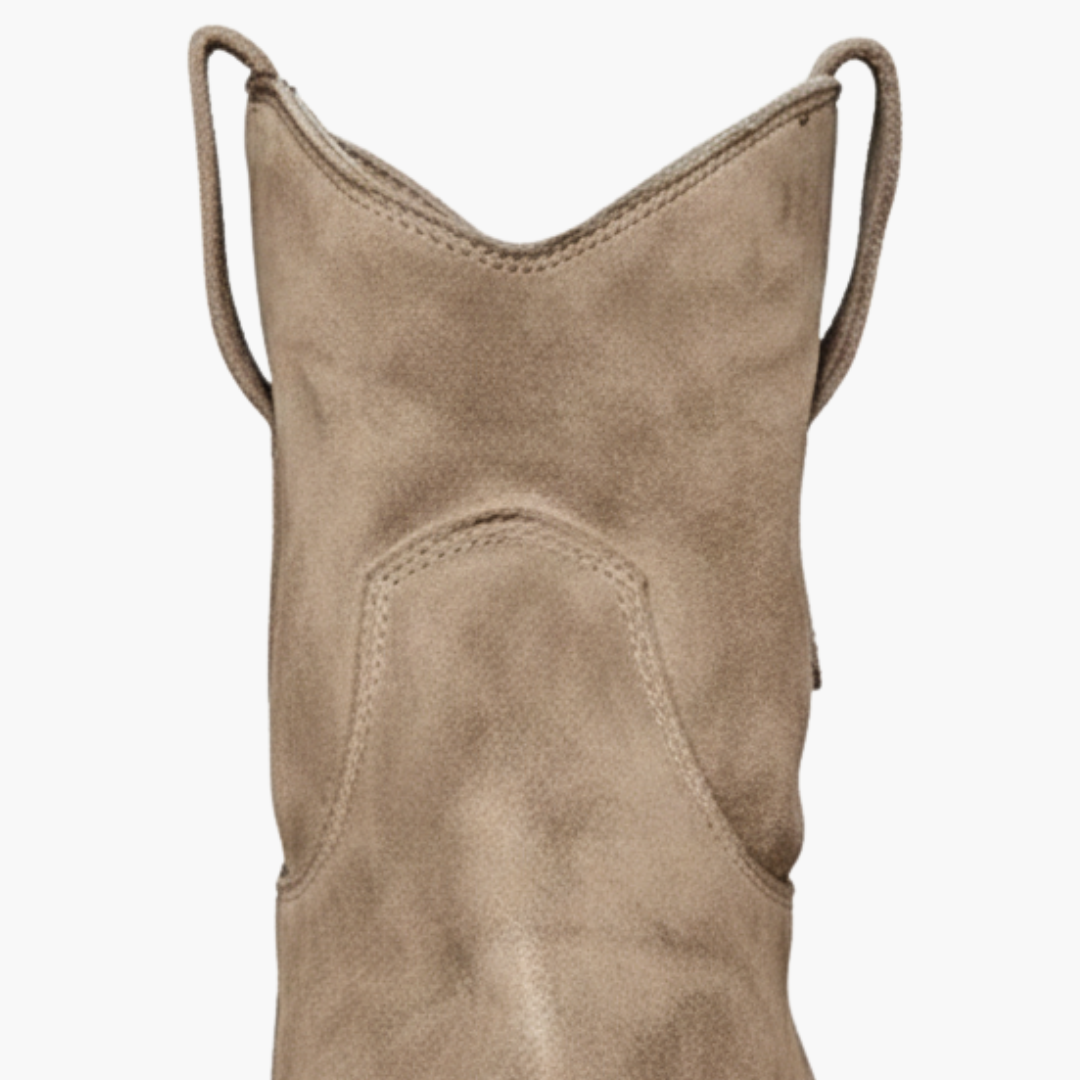 Close up details of a pair of brown ankle boots featuring a pull-on design and low stacked heel